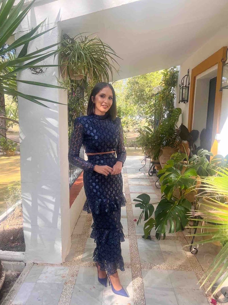 vestido de dos piezas azul marino de lentejuelas con manga larga, volantes en la falda y cinturón fino, de su dueña en un porche